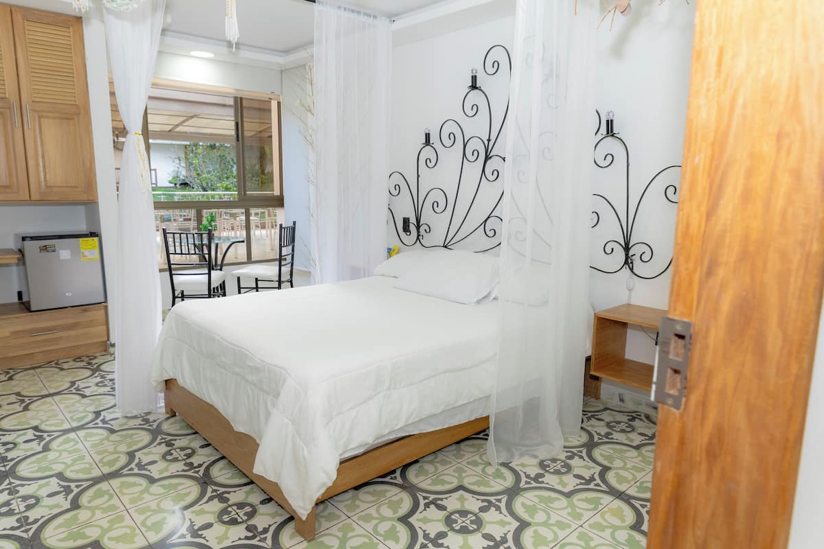 Un dormitorio con una cama, un armario de madera, una mesita y una silla.