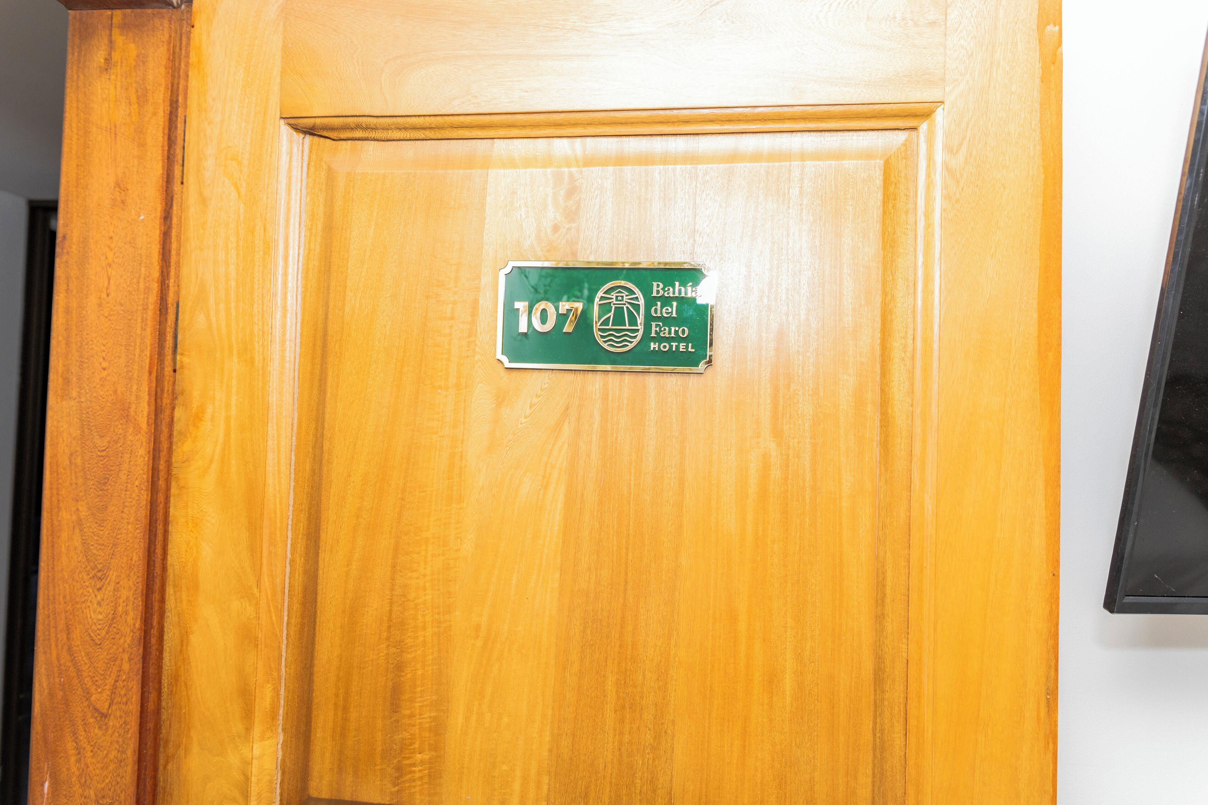 A wooden door with a hotel sign indicating room number 107 and the name 'Bahia del Faro Hotel'.