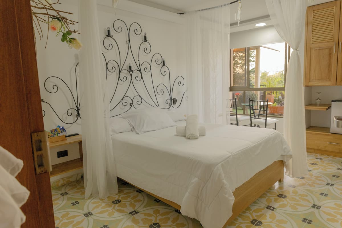 Un dormitorio con cama, mesita de noche y ventana.