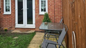 A brick house with a satellite dish, a glass door entrance, and a small patio with a table and chairs. - Entire house 🏠.  suitable for families and workers.  (Middlesbrough)