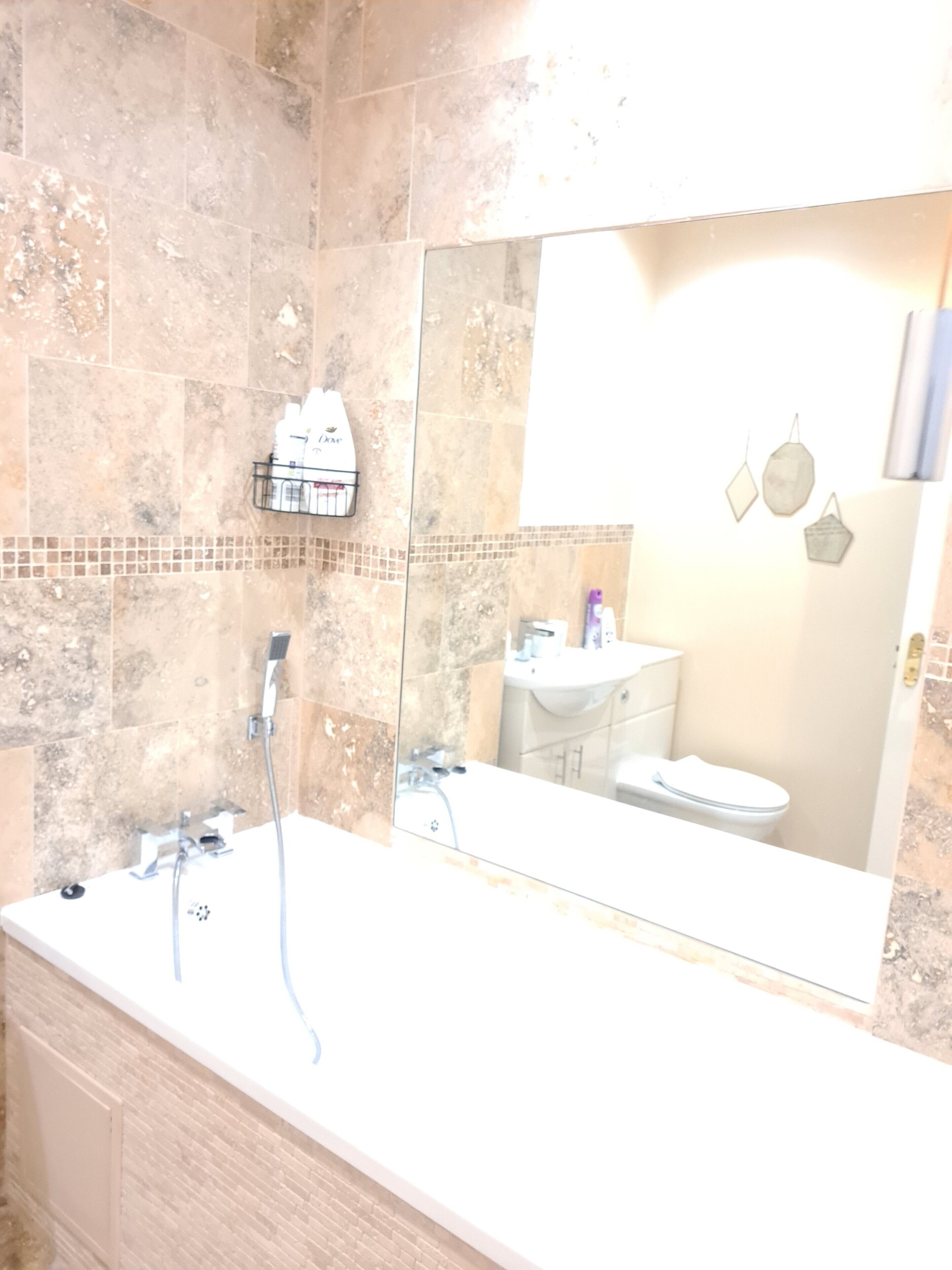 Une salle de bain avec un grand miroir, une baignoire et un lavabo.