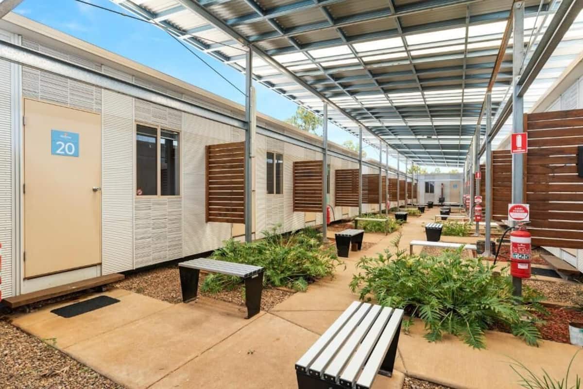 A row of portable cabins with a covered walkway, outdoor seating, and fire extinguishers.