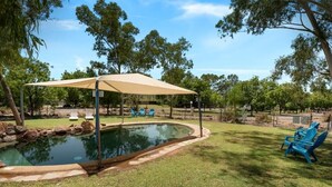 A backyard with a swimming pool, a covered patio area, and blue lawn chairs. - Discovery Parks - Cloncurry (Cloncurry)
