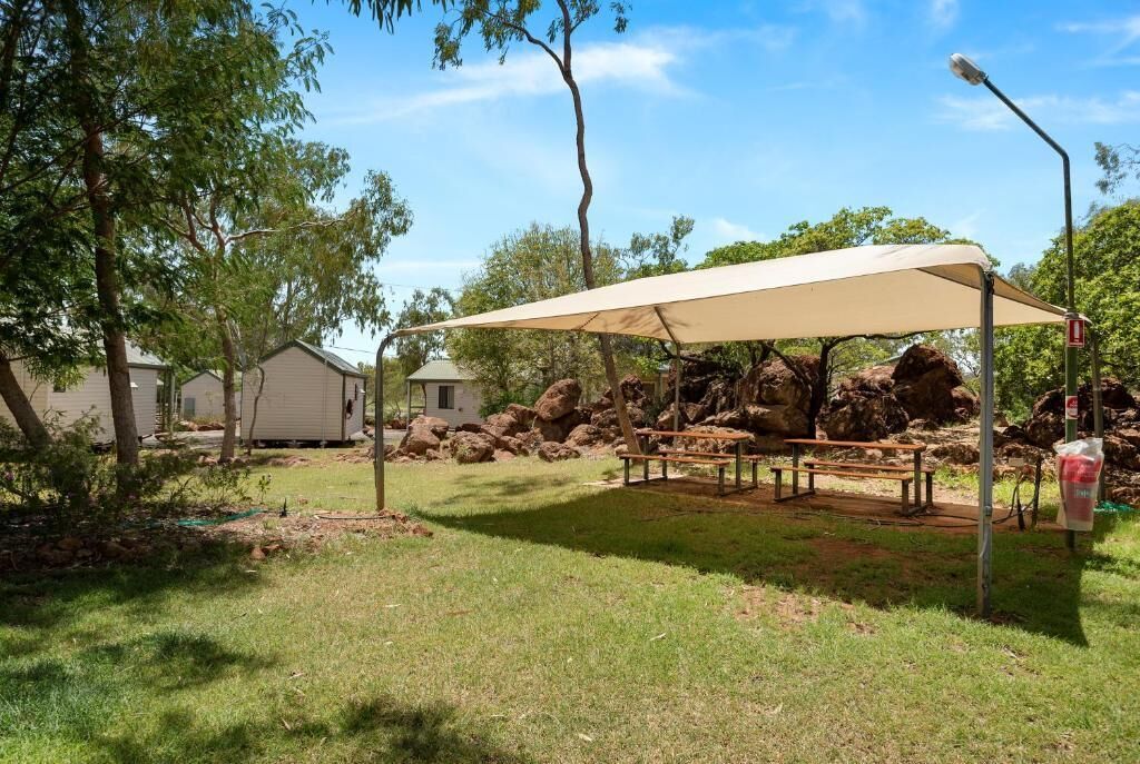 Un espace de pique-nique doté d’un auvent, d’une table de pique-nique et de bancs, entouré d’arbres et de rochers.