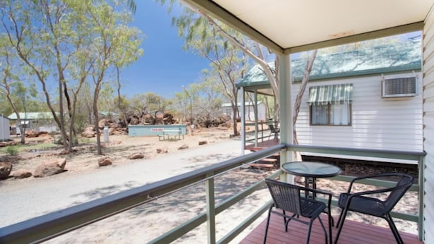 A covered outdoor area with a table and chairs, a signboard, and a view of a house and trees. - Discovery Parks - Cloncurry (Cloncurry)