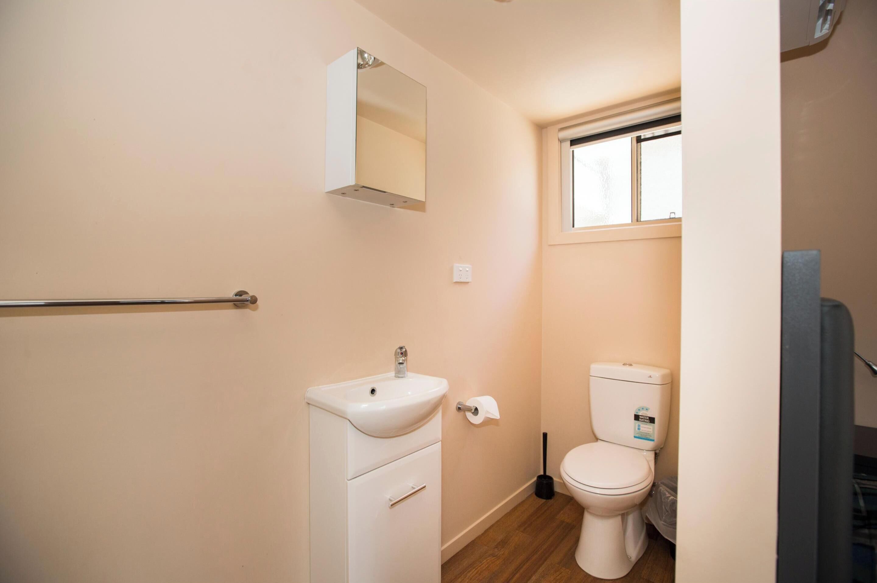 Un baño pequeño y funcional con un lavabo blanco, un inodoro y una ventana.
