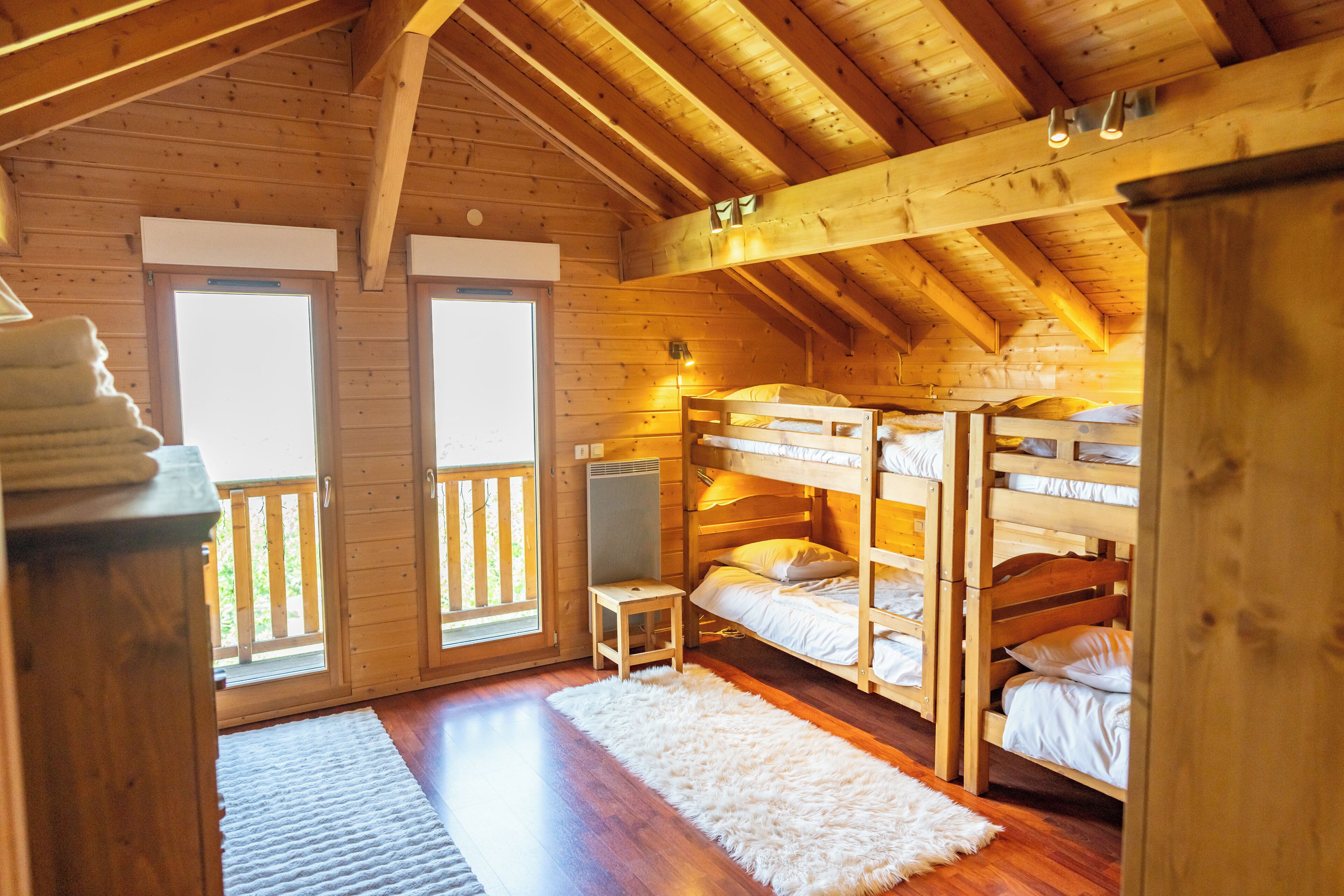A wooden cabin with bunk beds, a small table, and a white rug.