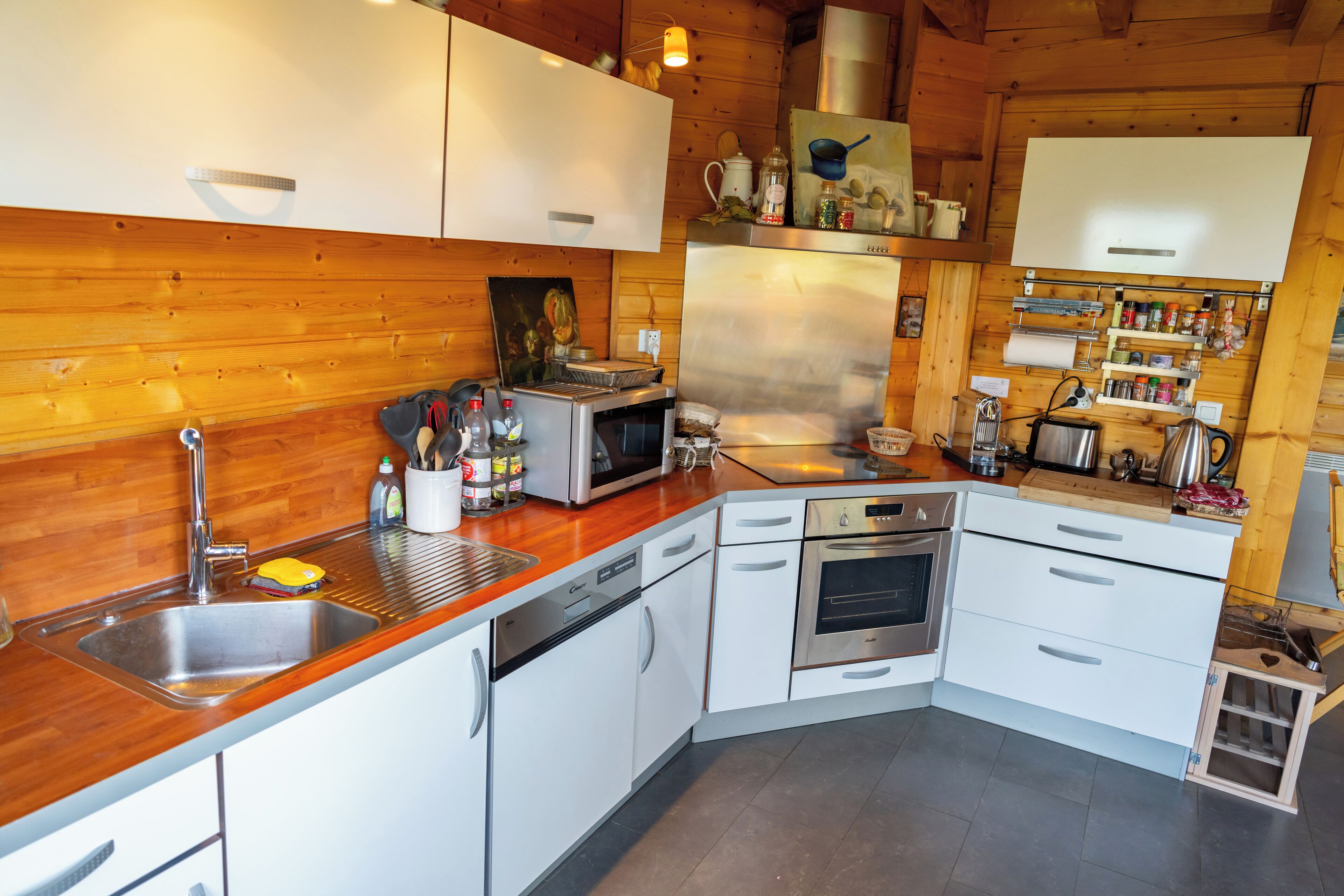 A modern kitchen with stainless steel appliances, white cabinetry, and wooden accents.