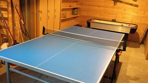 Et bordtennisbord i et rum med trævægge og hylder.