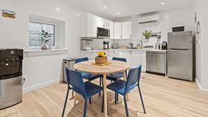 A modern kitchen with white cabinets, a stainless steel refrigerator, a microwave, and a dining area with blue chairs. - 2BR Apt + Sauna in Earth House, Minutes to Boulder (Superior)