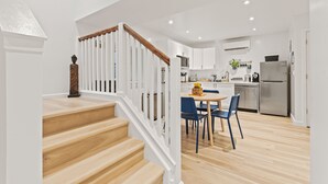 A modern kitchen with white cabinets, a stainless steel refrigerator, and a dining area with blue chairs. - 2BR Apt + Sauna in Earth House, Minutes to Boulder (Superior)