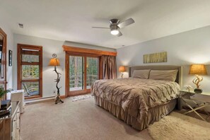 A bedroom with a large bed, two bedside lamps, a ceiling fan, and a view of the outdoors through a sliding glass door. - A-Frame Of Mind: Mountain Escape (Beech Mountain)