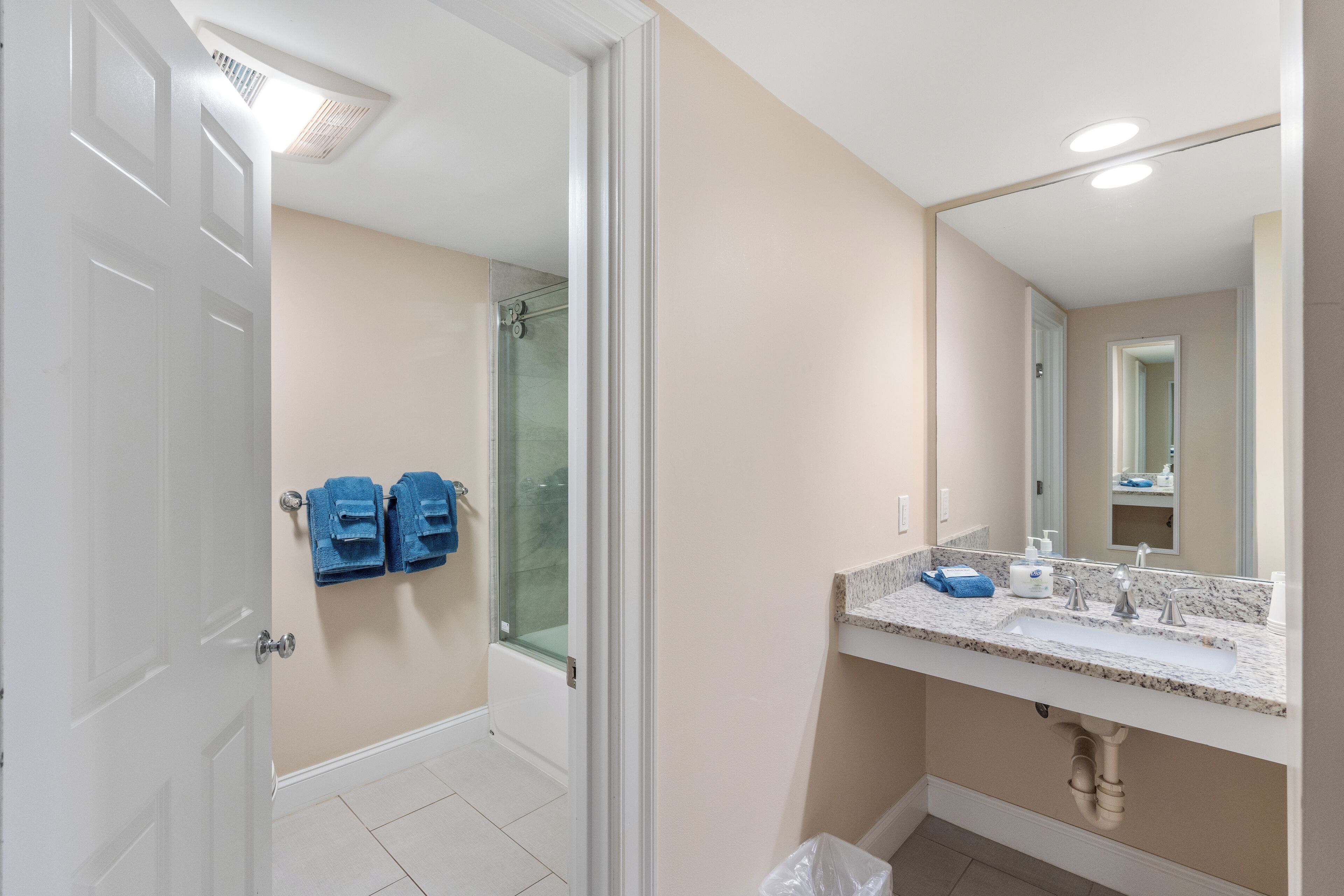 Un baño con ducha, lavamanos y espejo.