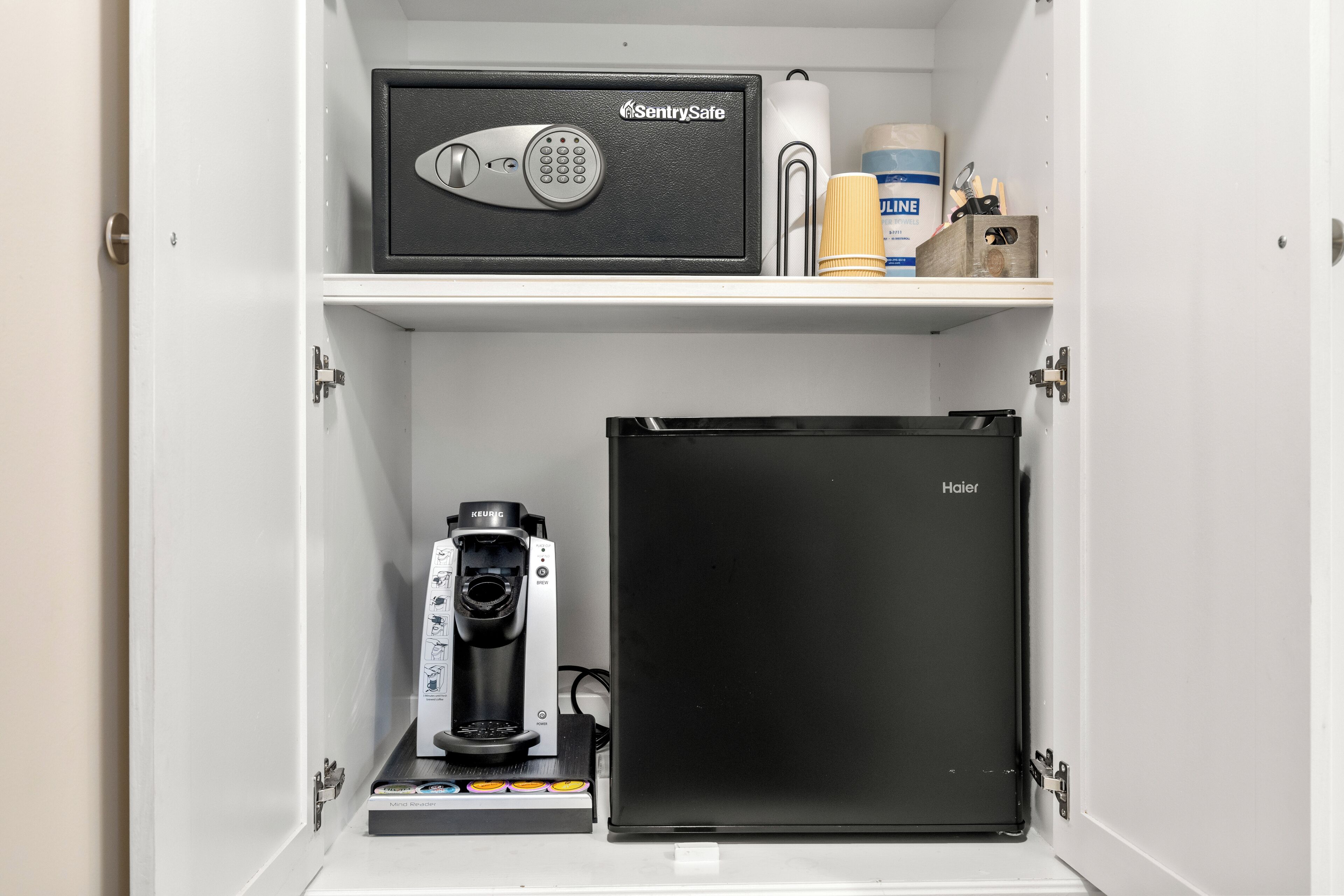 A minibar with a Keurig coffee machine, a Haier refrigerator, and a SentrySafe safe.