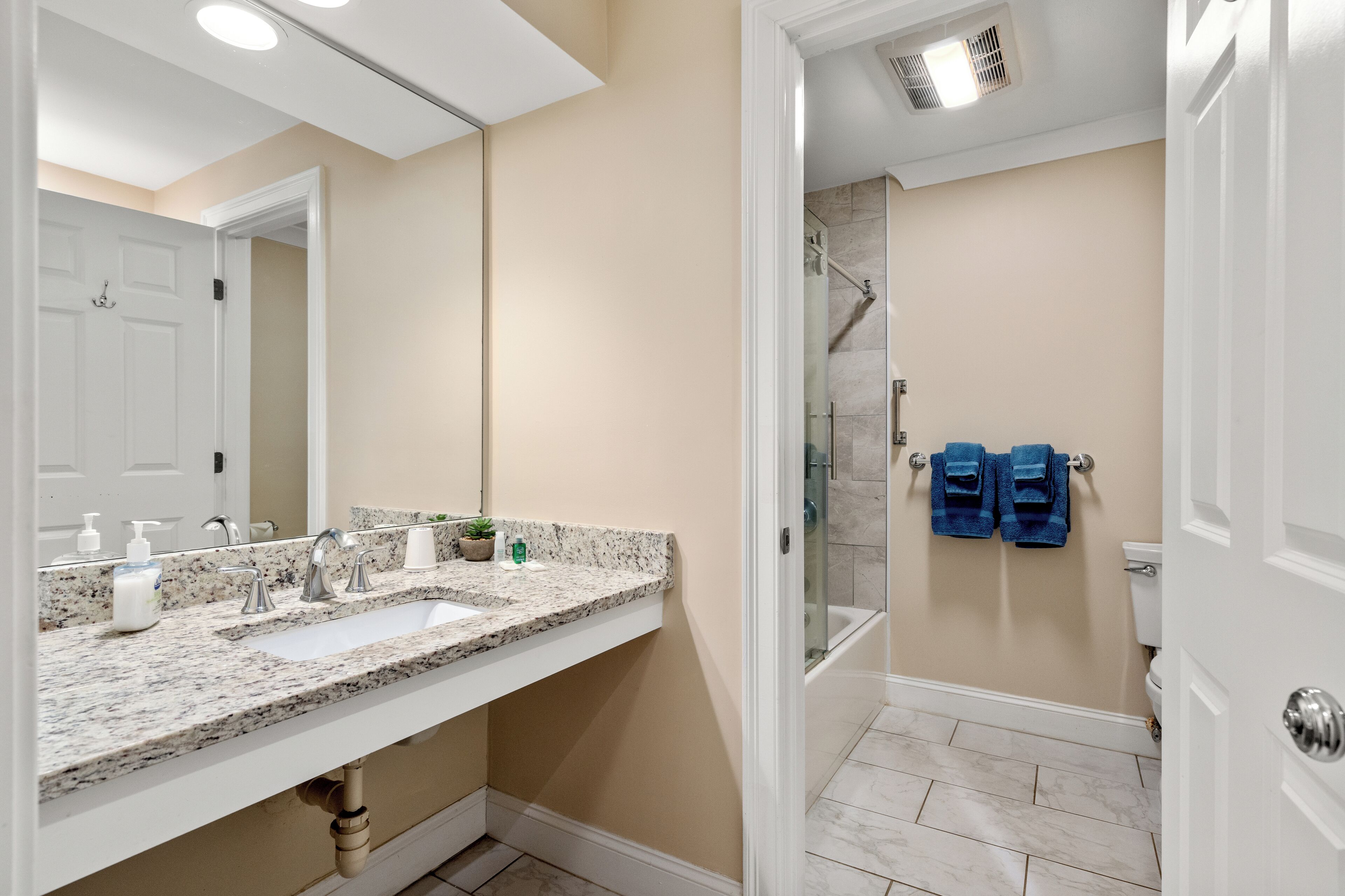 A bathroom with a white sink, two faucets, a mirror, and a shower area.
