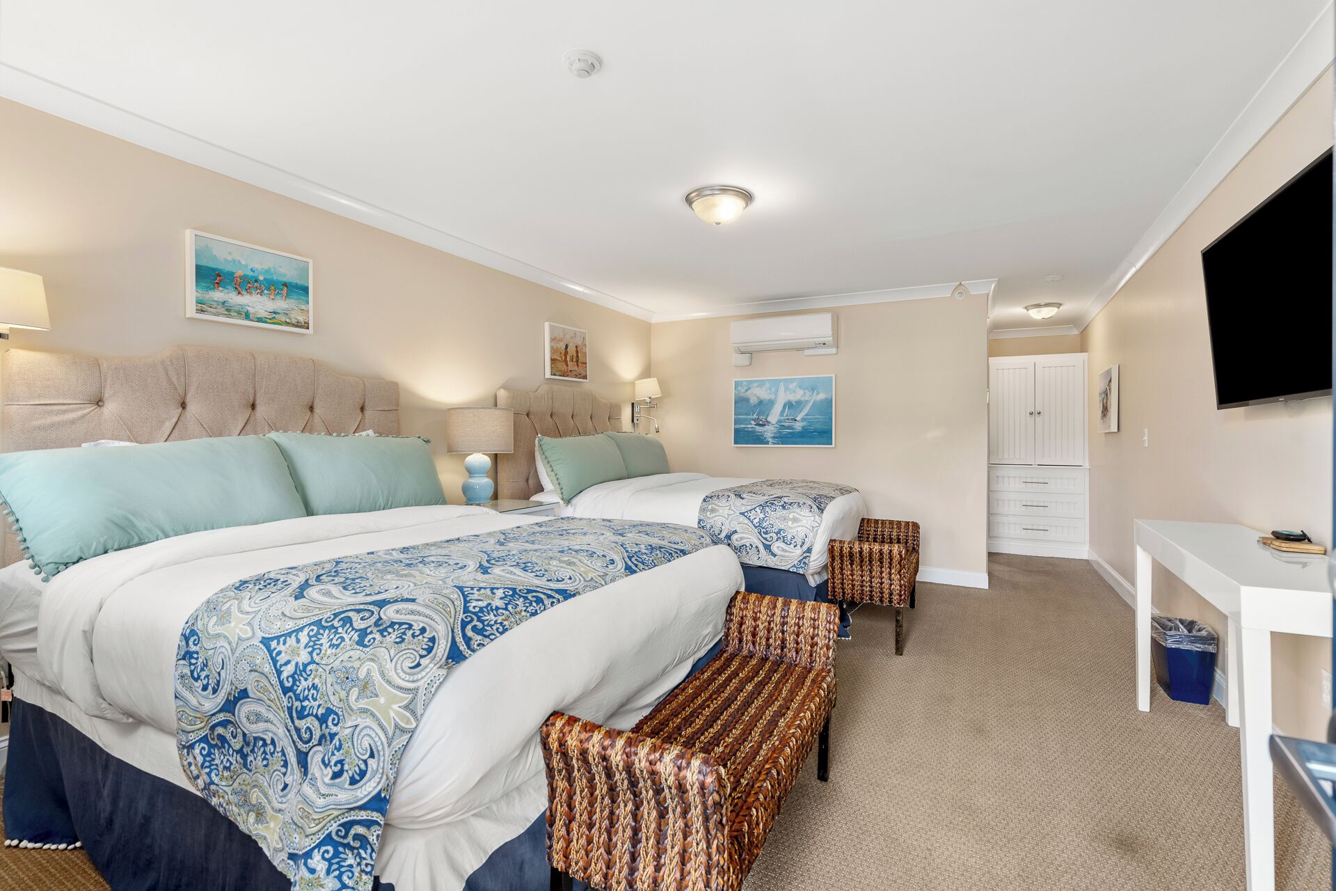 A hotel room with two beds, a TV, a desk, and a wardrobe.