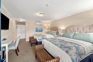 A hotel room with two beds, a desk, a chair, and a television. - Guest House Suites (Salisbury)