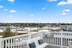A waterfront view from a balcony with a white railing, overlooking a marina with boats and a distant cityscape. - Guest House Suites (Salisbury)