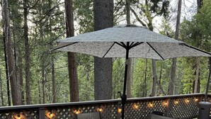 An outdoor patio with a round table and chairs, surrounded by a wooden deck and a lattice fence.