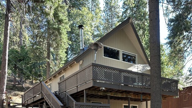 A two-story cabin with a deck, a fireplace, and a staircase leading to the upper level.