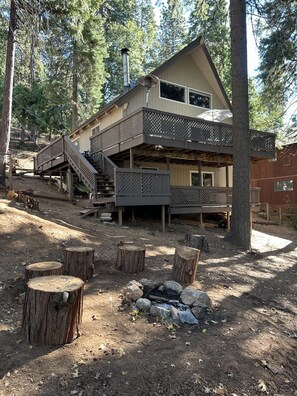 Une cabane à deux étages dotée d’une terrasse, d’une cheminée et d’un escalier menant à l’étage supérieur.