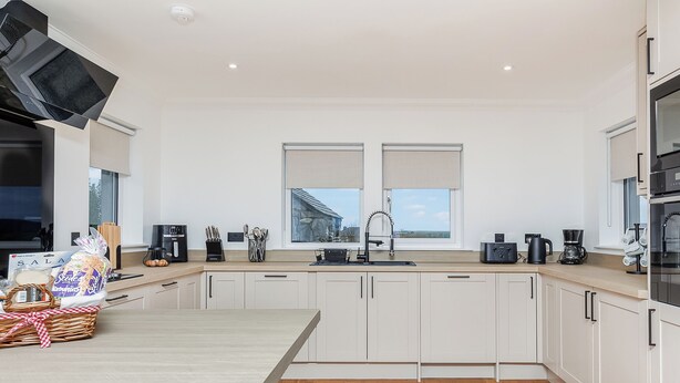 A modern kitchen with white cabinets, a wooden countertop, and a large window. - 3 bedroom accommodation in South Boisdale (South Boisdale)