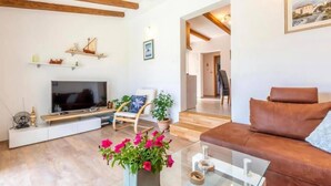 A living room with a TV, a brown leather sofa, a glass coffee table, and a potted plant with pink flowers. - Amazing home in Dracevica (Dracevica)
