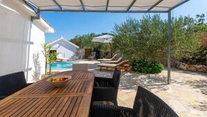 A covered outdoor area with a pool, lounge chairs, and a dining table with a bowl of fruit. - Amazing home in Dracevica (Dracevica)