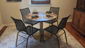 Un comedor con una mesa redonda, cuatro sillas y una ventana con persianas.