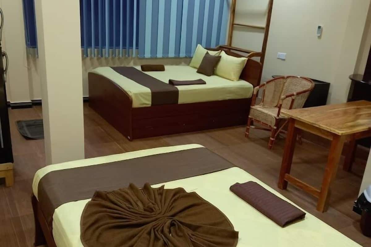 Una habitación de hotel con dos camas, una mesa de comedor y una silla.