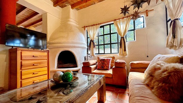 A cozy living room with a stone fireplace, wooden furniture, and a television. - Sandunga Lago Tzintzuntzan (Tzintzuntzan)
