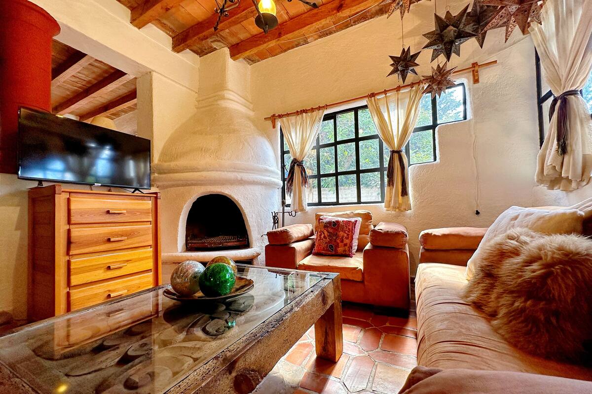 Ein gemütliches Wohnzimmer mit Kamin aus Stein, Holzmöbeln und einem Fernseher.