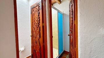 A wooden door with intricate carvings, a tiled floor, and a blue-tiled wall.
