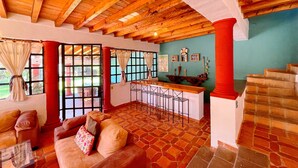 A spacious living area with a wooden ceiling, a stone-tiled floor, a bar area, and a staircase. - Sandunga Lago Tzintzuntzan (Tzintzuntzan)
