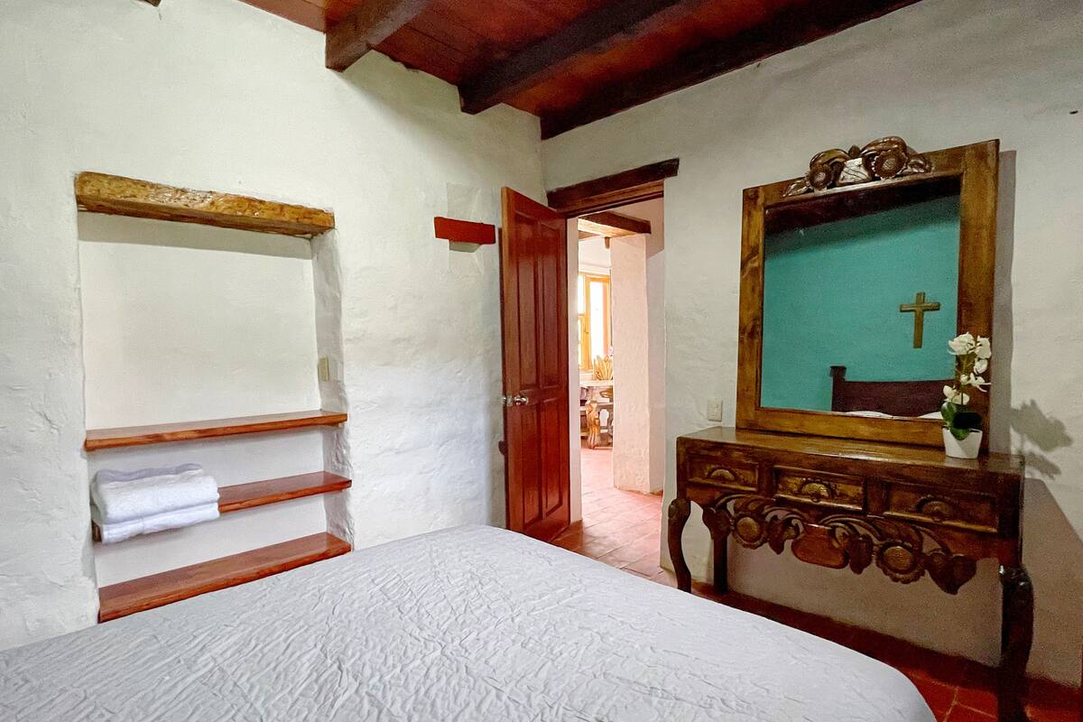 Ein Schlafzimmer mit einem Bett, einem hölzernen Schminktisch, einem Spiegel und einem Regal.