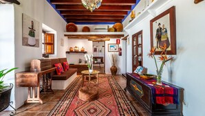 Un intérieur traditionnel avec un plafond en bois, un tapis à motifs, un canapé, une table basse et un buffet agrémenté d’objets décoratifs.