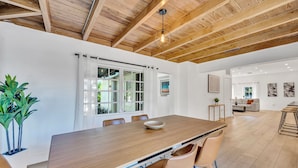 Een moderne eethoek met een houten tafel, lederen stoelen en een groot raam met gordijnen.