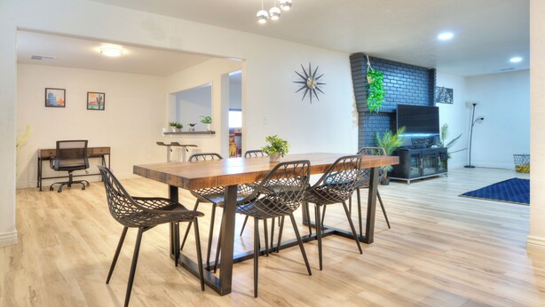 Ruime eethoek met een houten tafel, moderne stoelen, een accentmuur van baksteen en een plafondlamp.