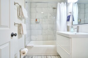 A bathroom with a bathtub, a shower, a sink, and a toilet. - Modern retreat with games room in central location! (Page)