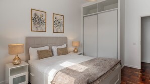 Ein Schlafzimmer mit einem Bett, zwei Nachttischen mit Lampen, einem Kleiderschrank und zwei Wandbildern.