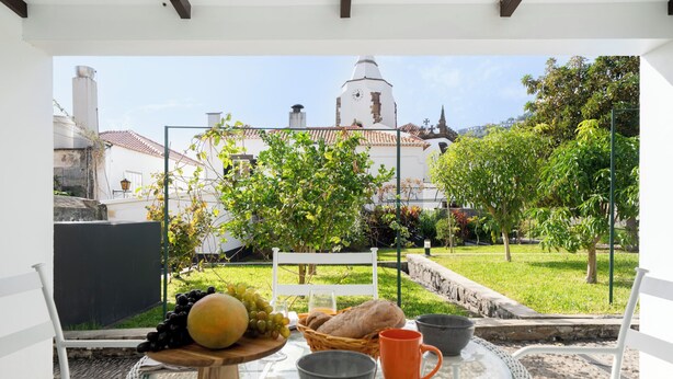 Ein Tisch mit einem Brotkorb, einer Schüssel und einer Tasse, vor einer Aussicht auf ein weißes Gebäude mit einem Glockenturm.