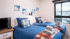 A hotel room with two beds, a TV, a lamp, and artwork on the wall. - Alpine Retreat by Revelstoke Vacations (Revelstoke)