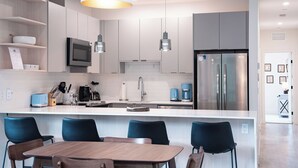 A modern kitchen with a central island, stainless steel appliances, and blue chairs. - Alpine Retreat by Revelstoke Vacations (Revelstoke)