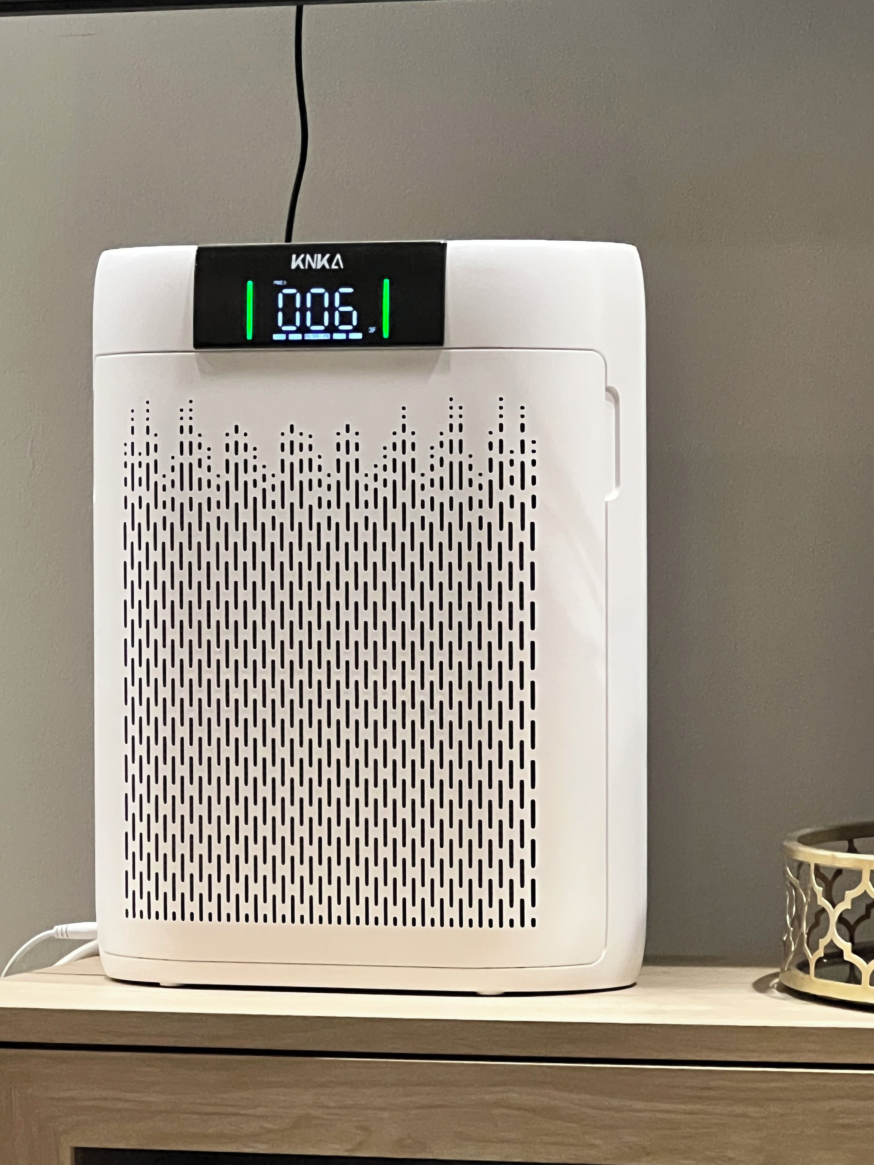 A white portable heater with a digital display on top, placed on a wooden surface.