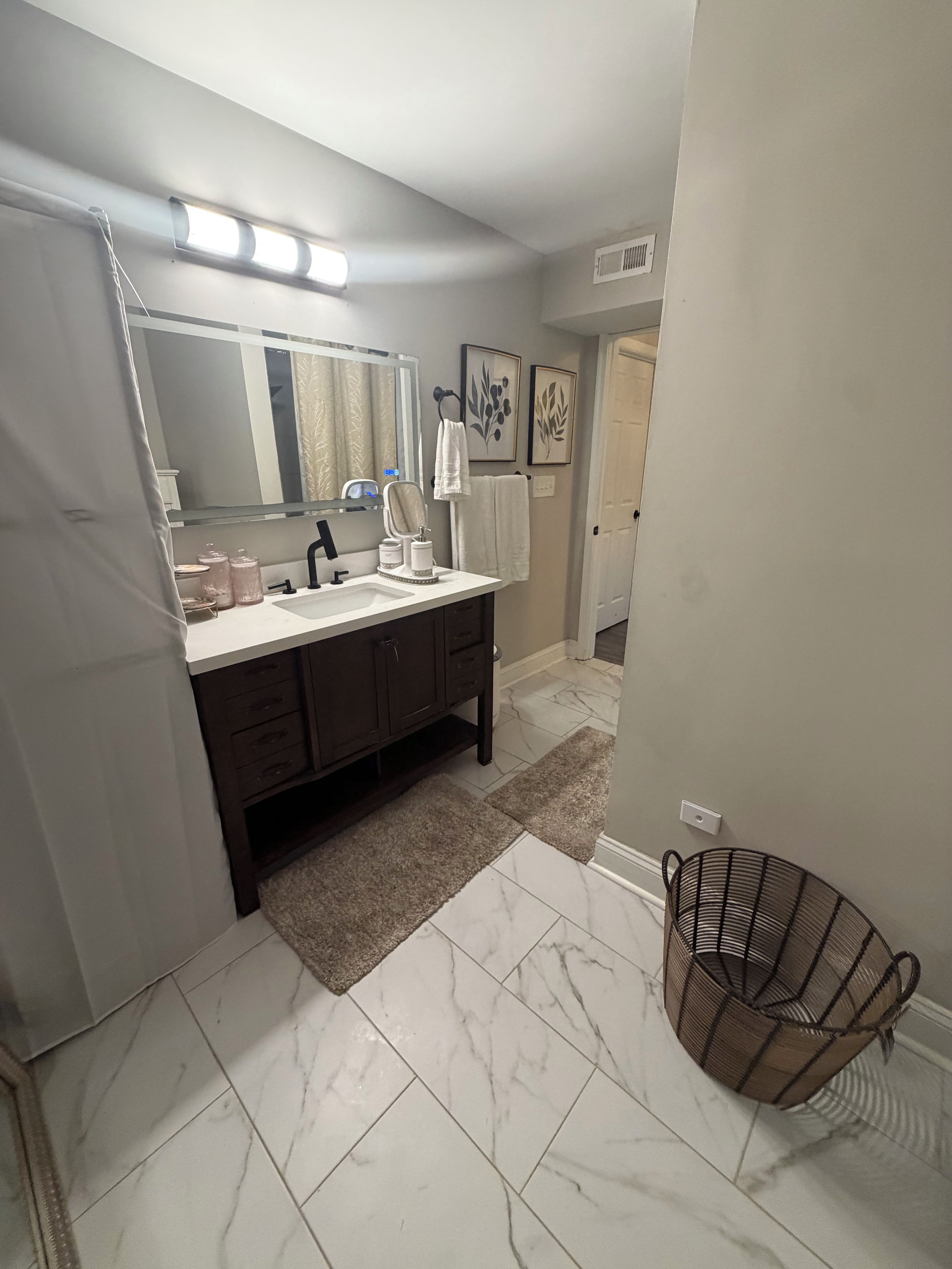 A bathroom with a dark wooden vanity, a white sink, a mirror, and a towel rack.