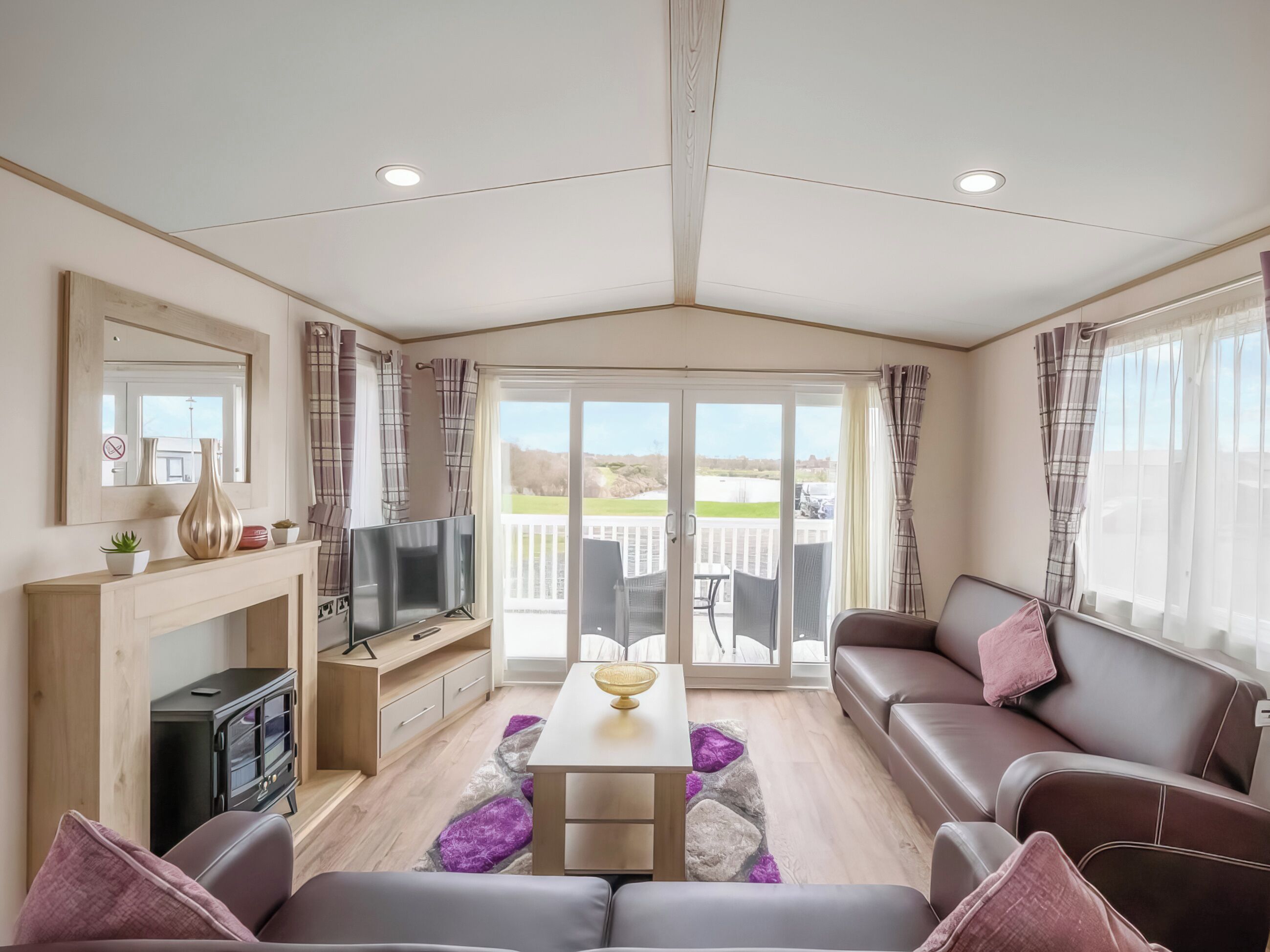 Een moderne woonkamer met een open haard, een flatscreen televisie, een bank en een eettafel.