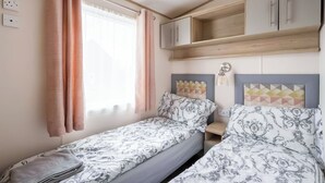 A bedroom with two single beds, a wooden cabinet, a bedside table, and a window with curtains. - 2 bedroom accommodation in Retford (Retford)