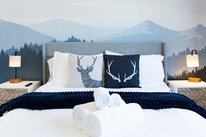 Ein Bett mit zwei Kissen, einer blauen Decke und zwei zusammengerollten Handtüchern.