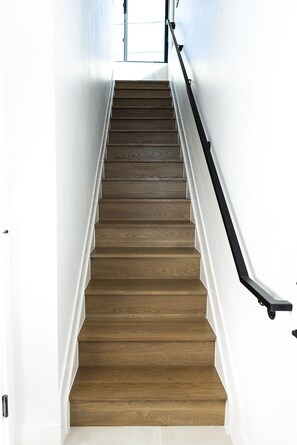 Eine Holztreppe mit weißen Wänden und einem schwarzen Geländer.