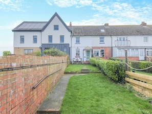 A residential area with two houses, a brick wall, and a grassy lawn. - We love this cosy cottage, located just a two minute walk from the beach. (Fareham)